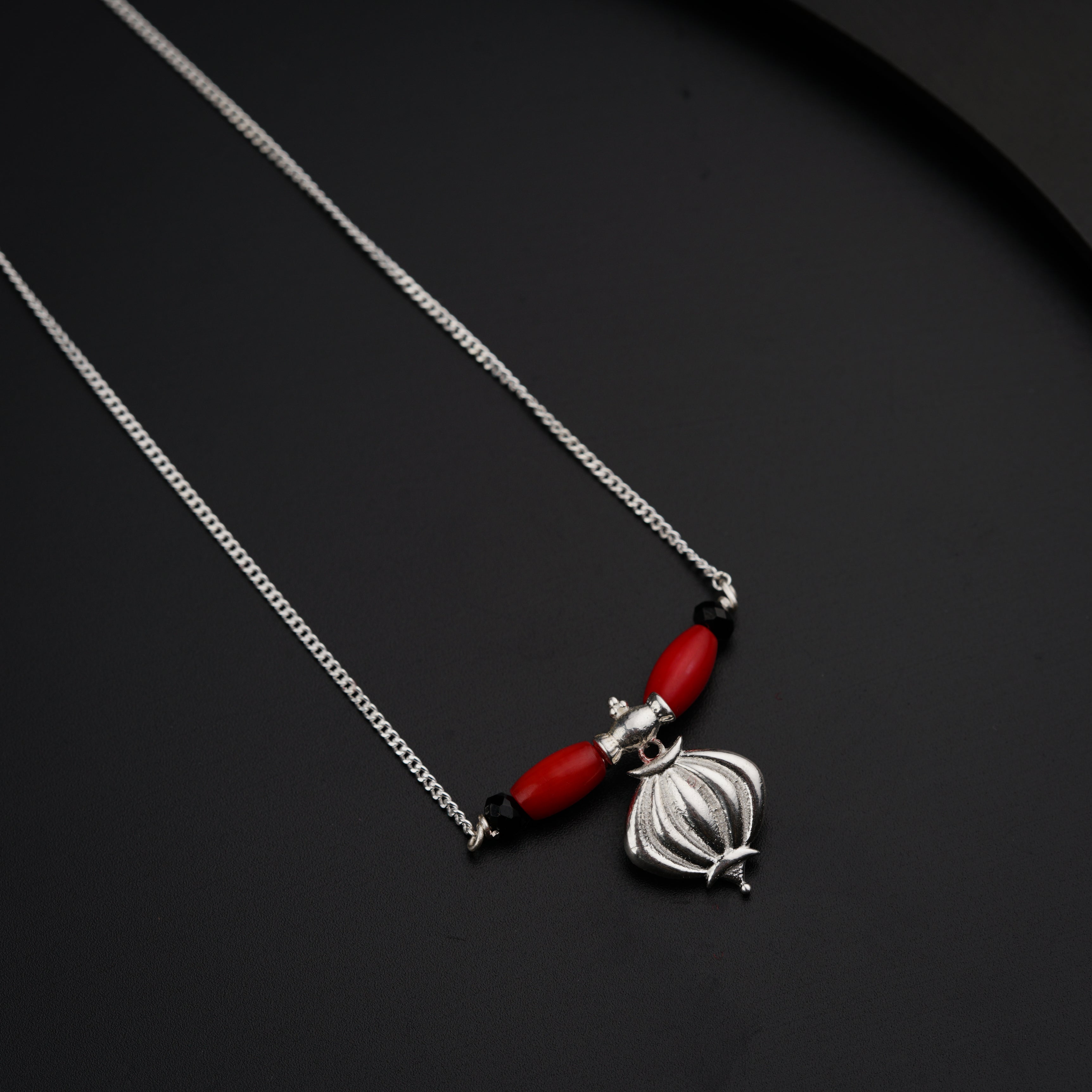 a red and silver necklace on a black surface