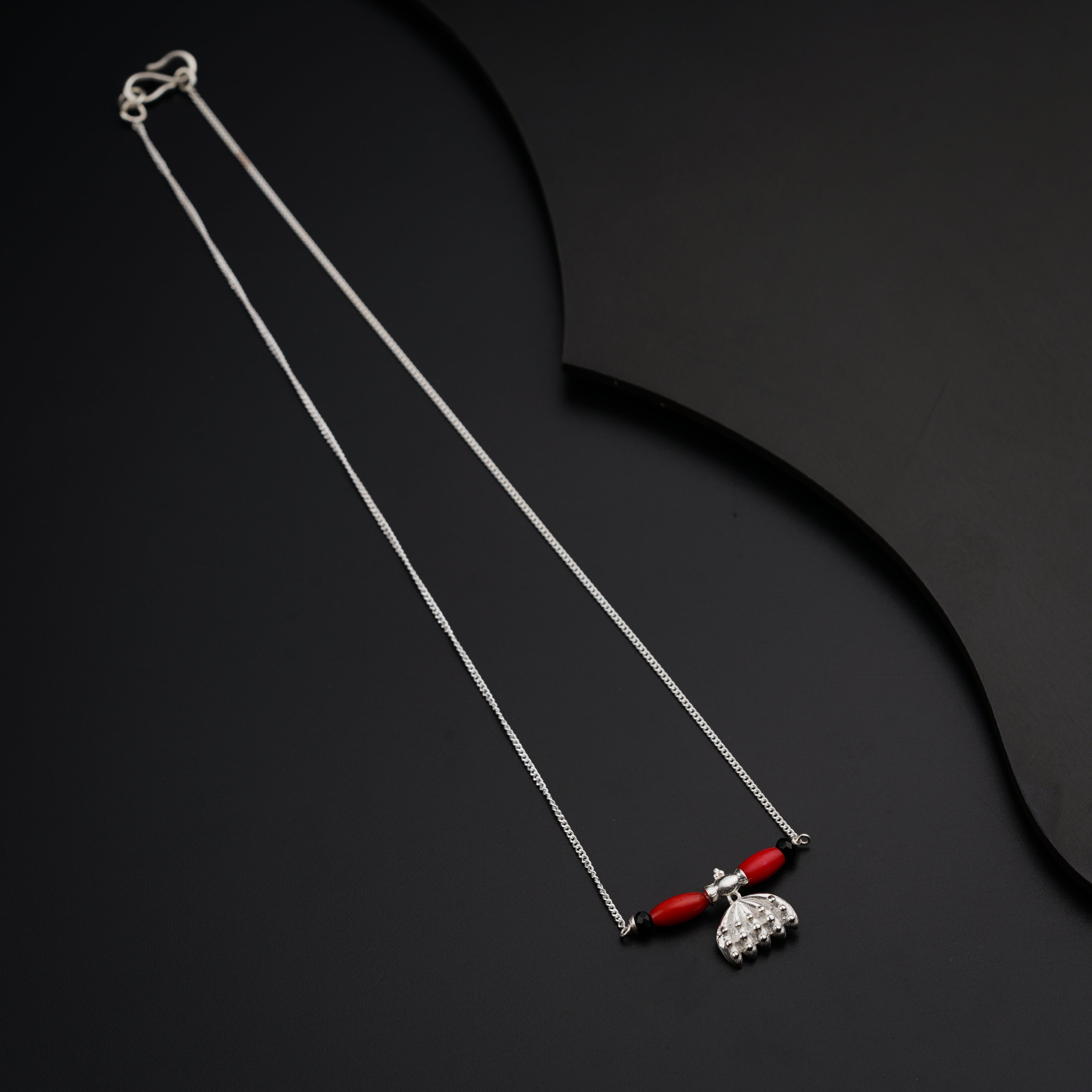 a pair of red and silver necklaces on a black surface
