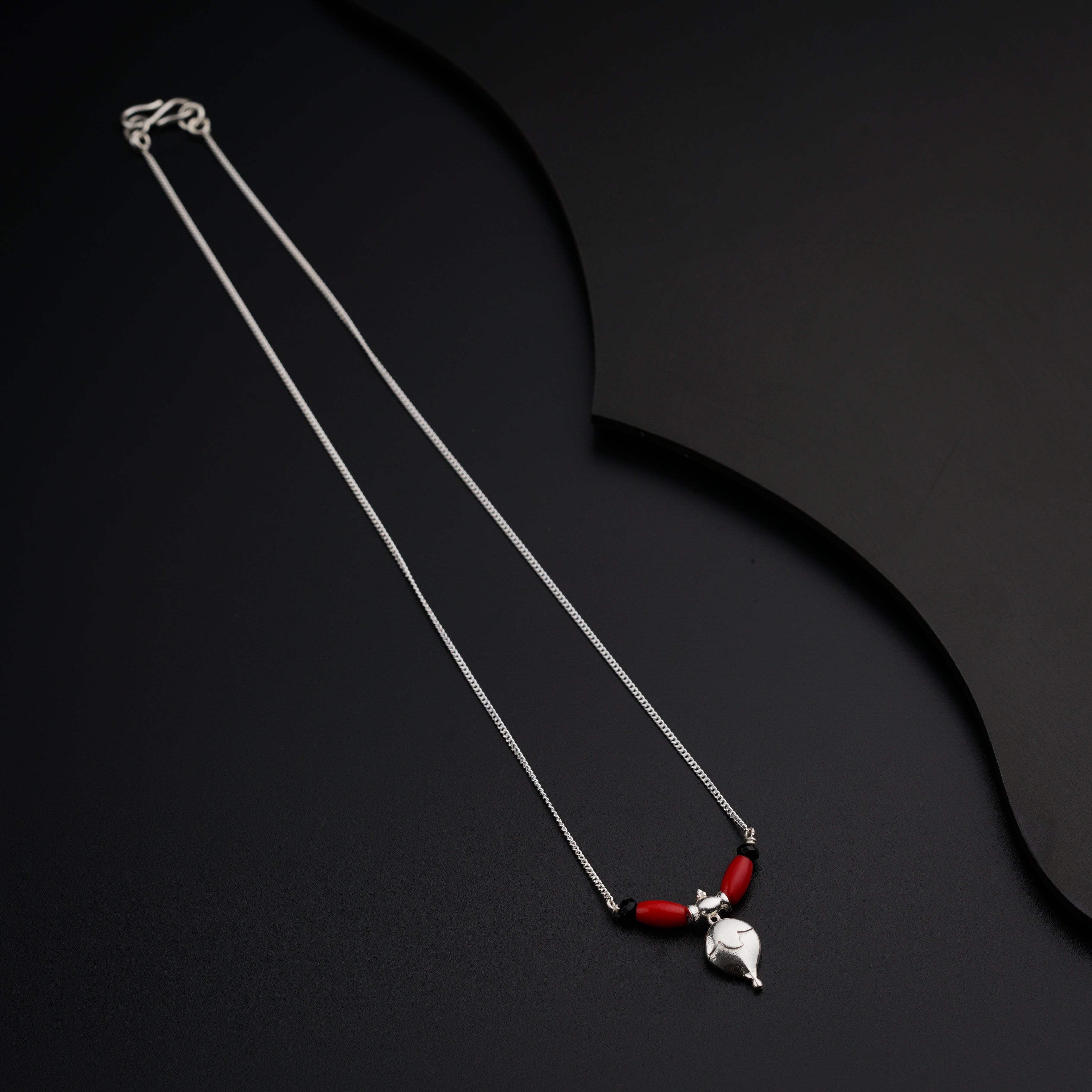 a necklace with a red bead hanging from a silver chain