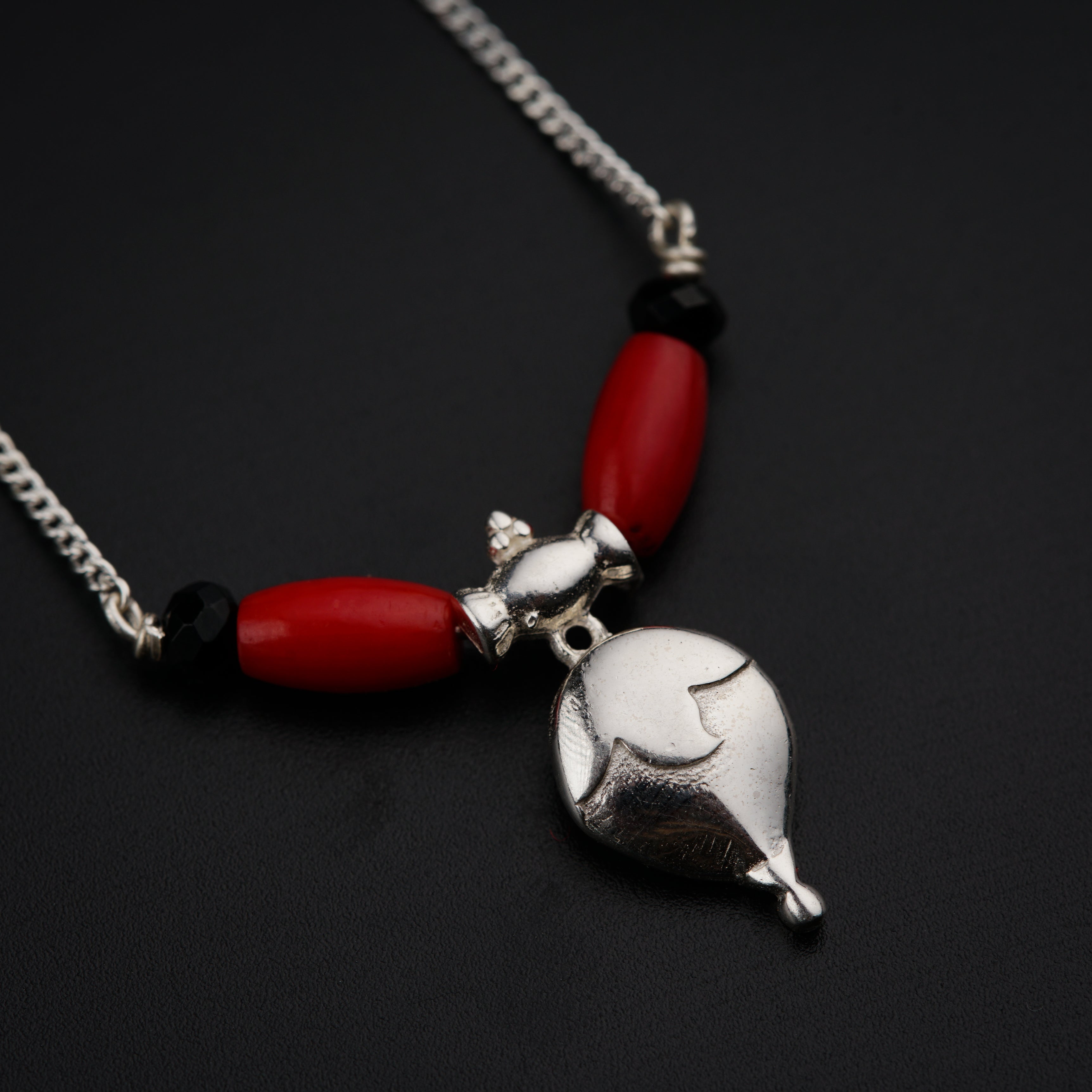 a red and silver necklace on a black surface