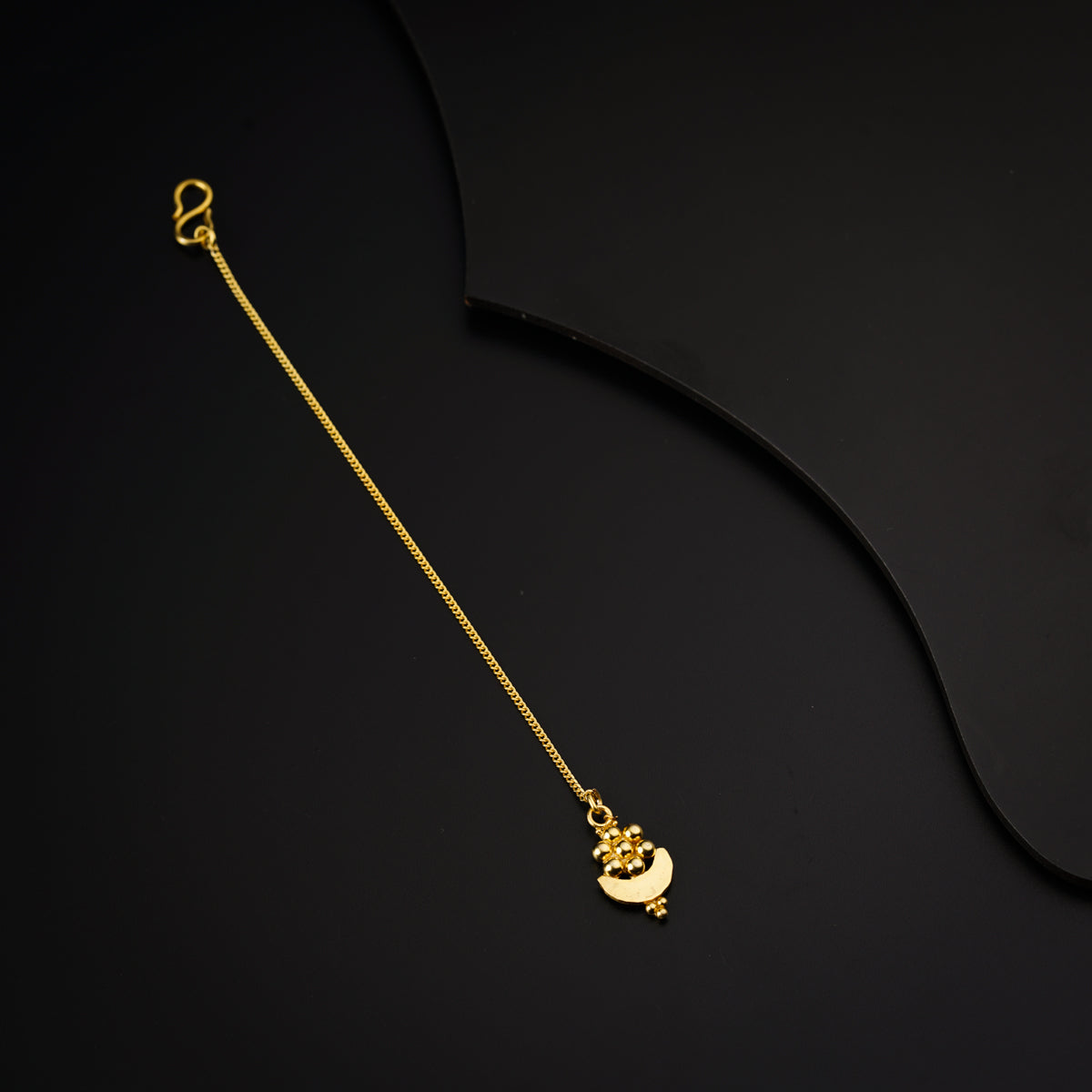 a gold necklace with a heart on a black background