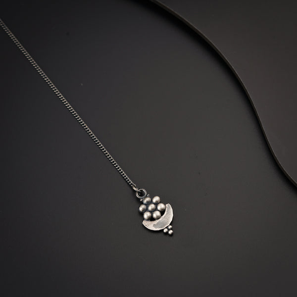 a silver necklace on a black surface