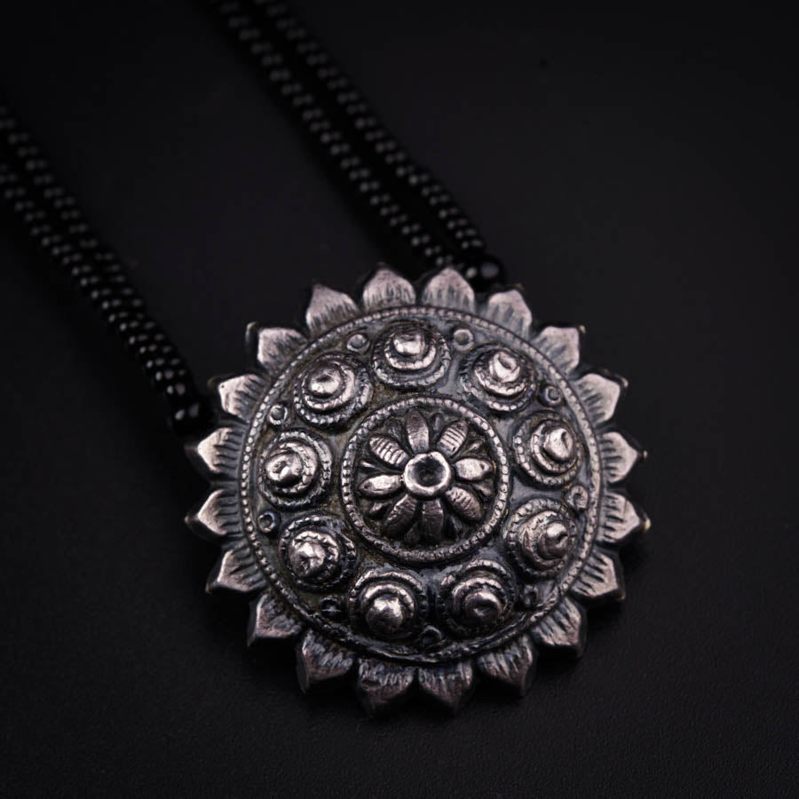 a necklace with a flower design on a black background