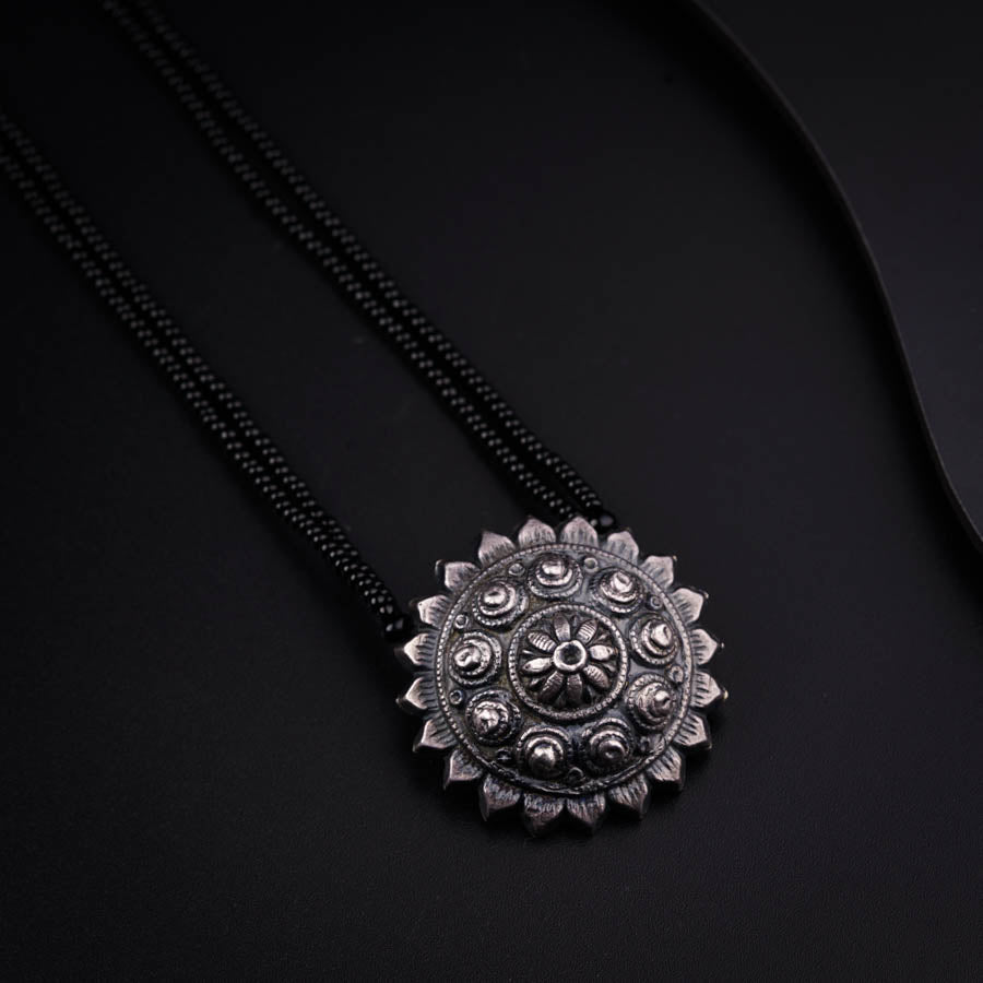 a black necklace with a flower design on it