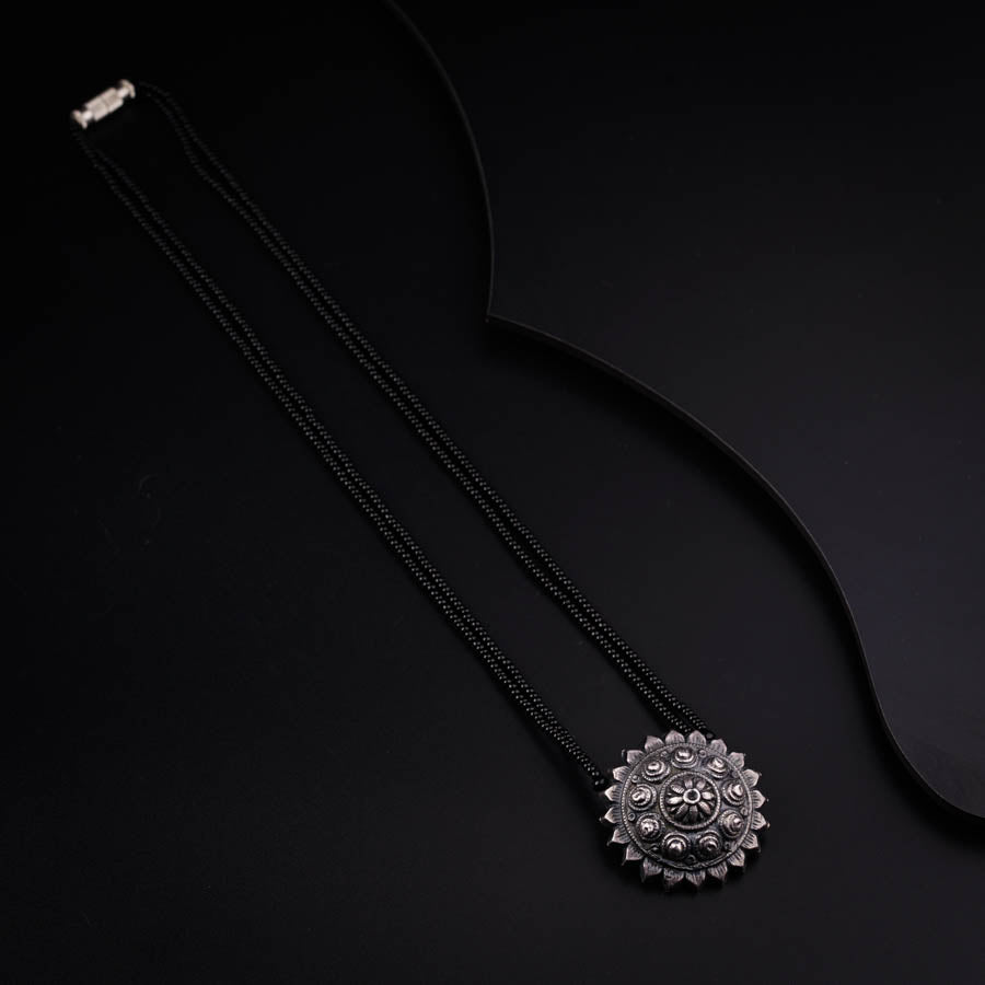 a black necklace with a flower design on it