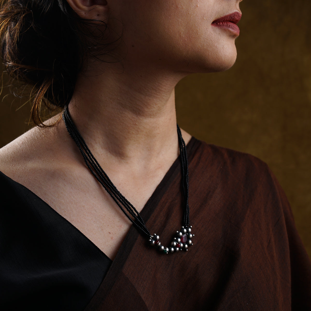 a woman wearing a brown shirt and a black necklace