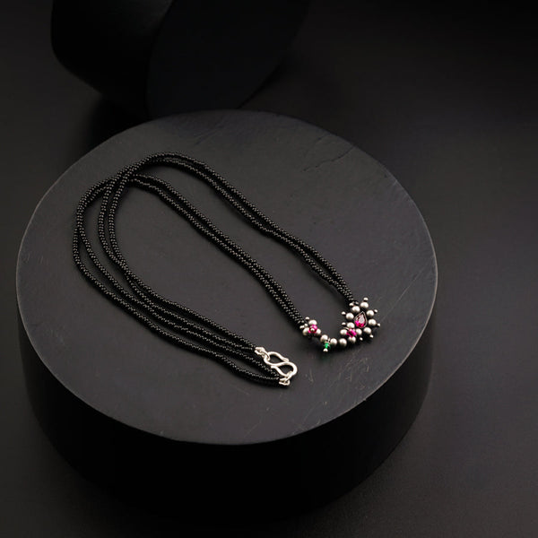 a necklace with beads and a pendant on a black plate