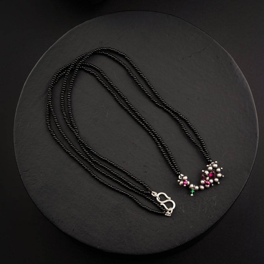 a black beaded necklace with pink and green beads