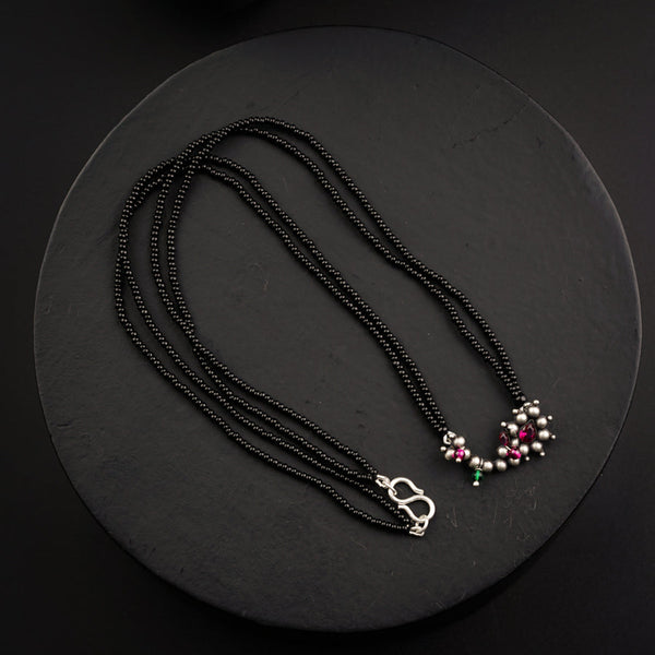a black beaded necklace with pink and green beads