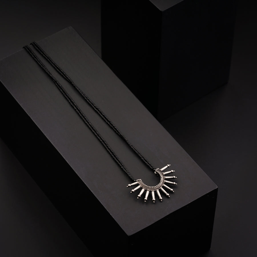 two necklaces sitting on top of a black box