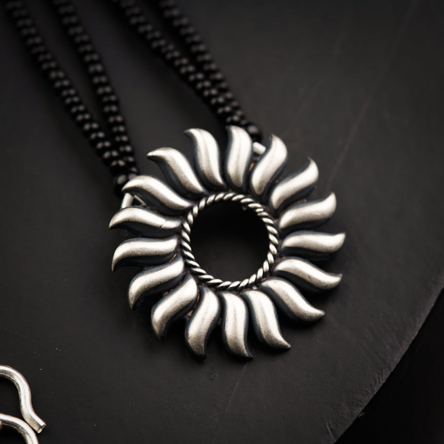 a necklace with a spiral design on a black surface