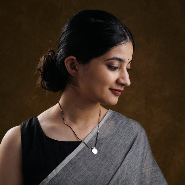 a woman wearing a necklace and a black top