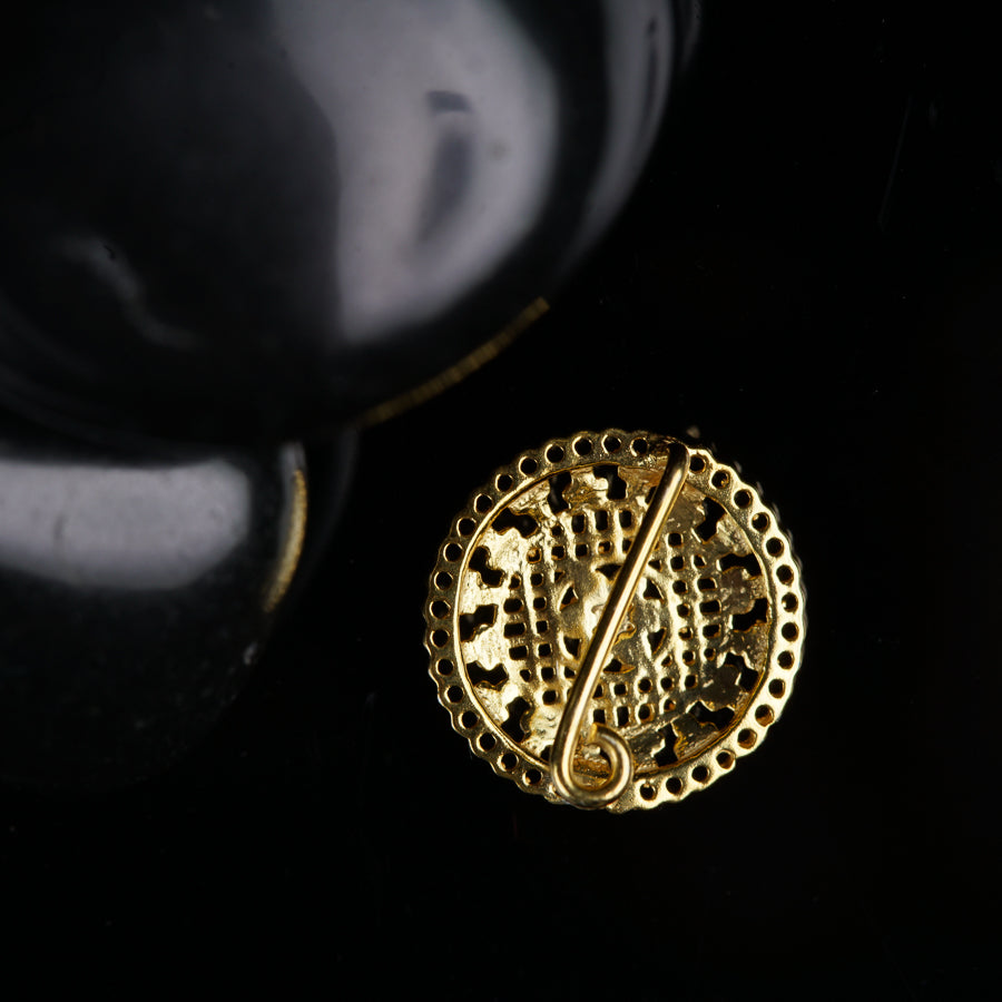 a gold brooch sitting on top of a black surface