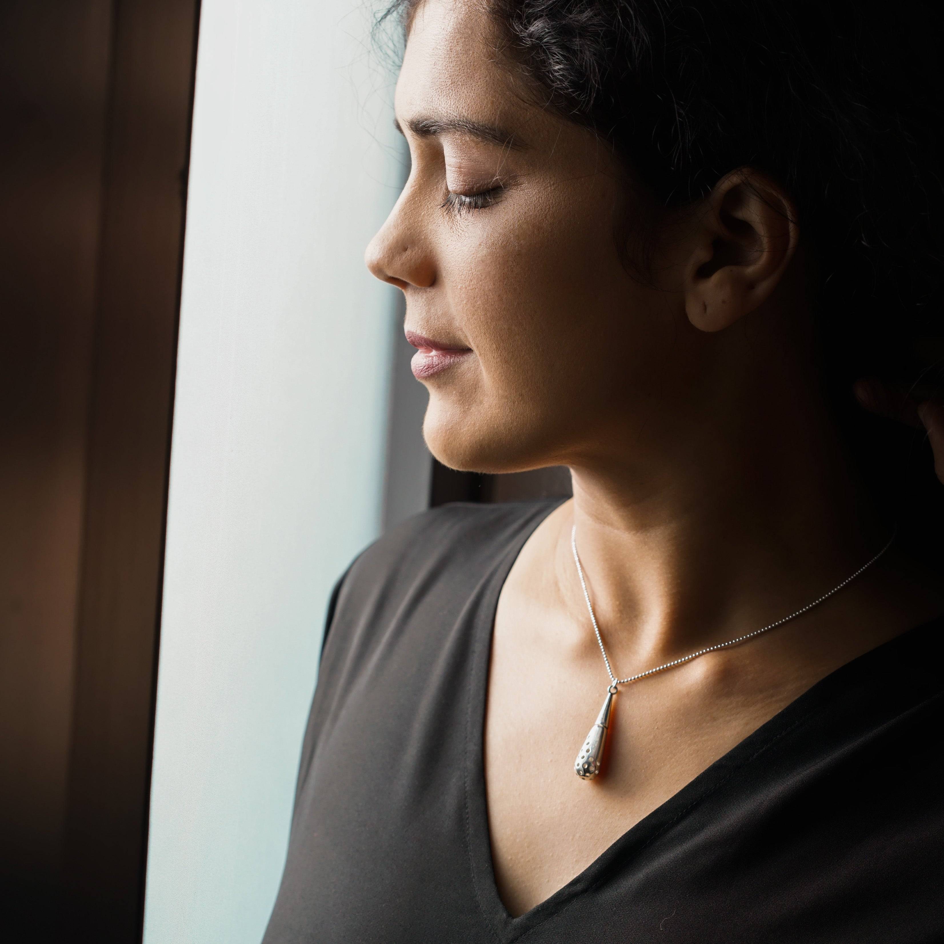 a woman looking out a window with a necklace on