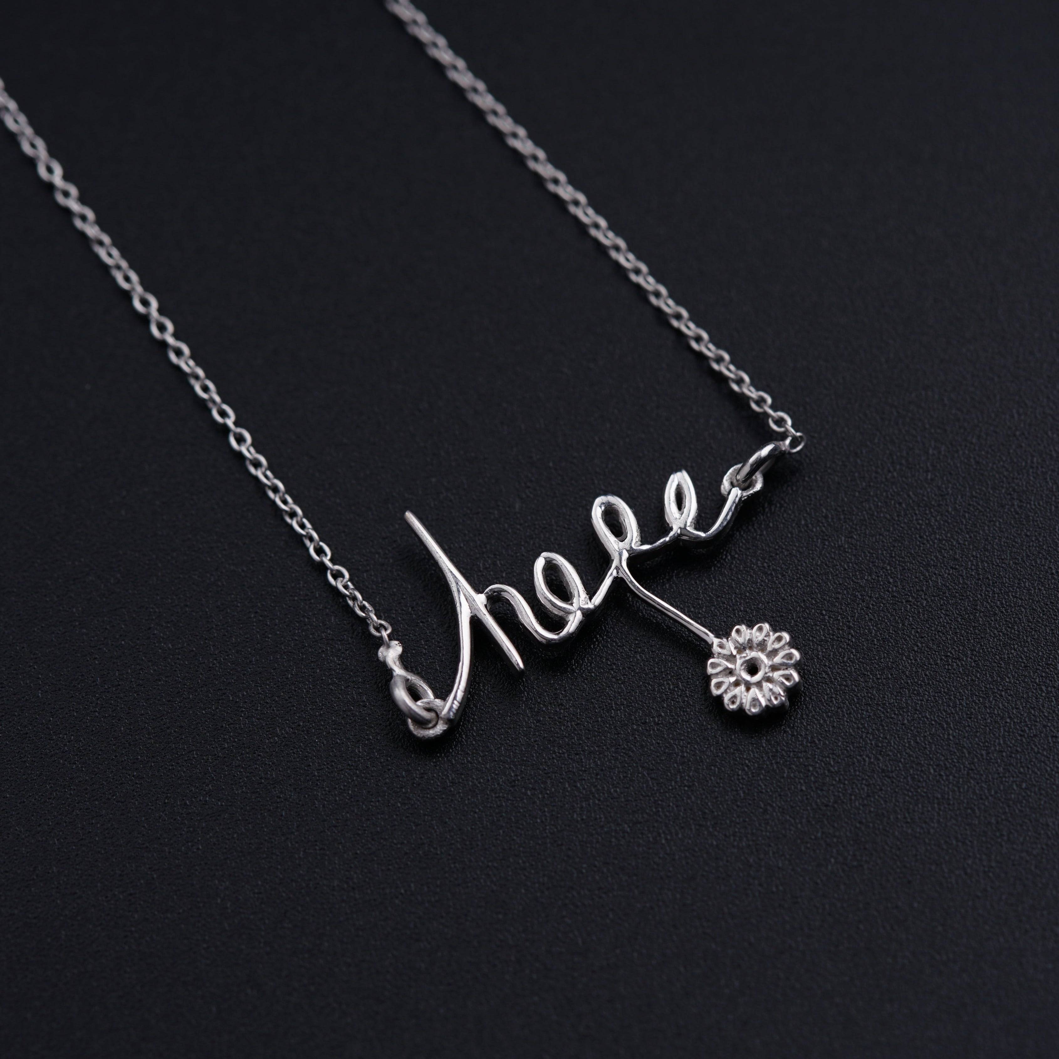 a silver necklace with a name and a flower on it