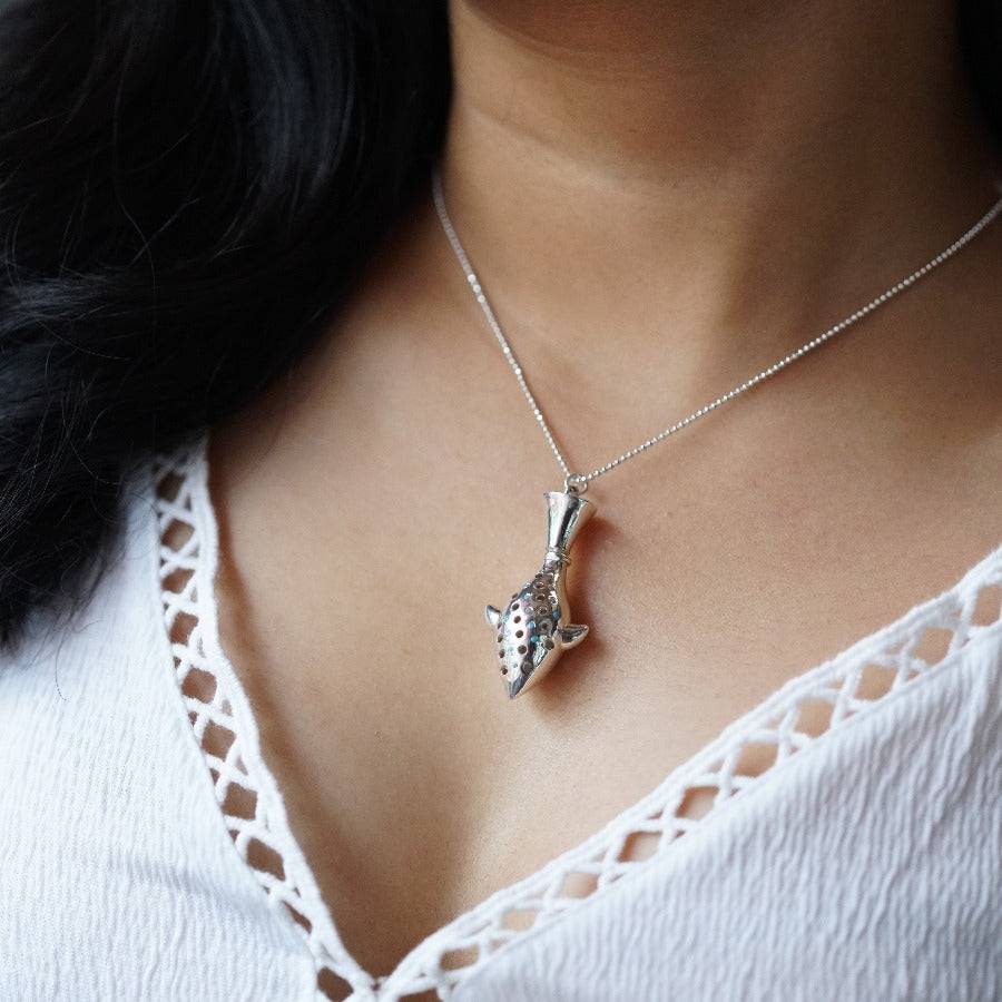 a woman wearing a necklace with a fish on it
