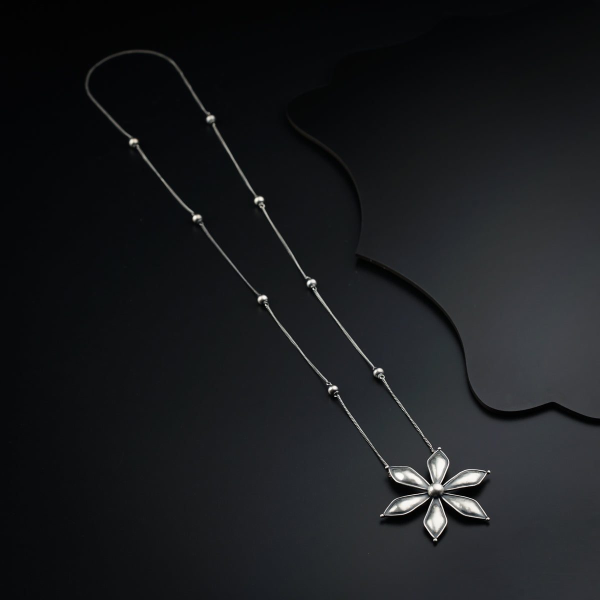 a necklace with a flower on a black background