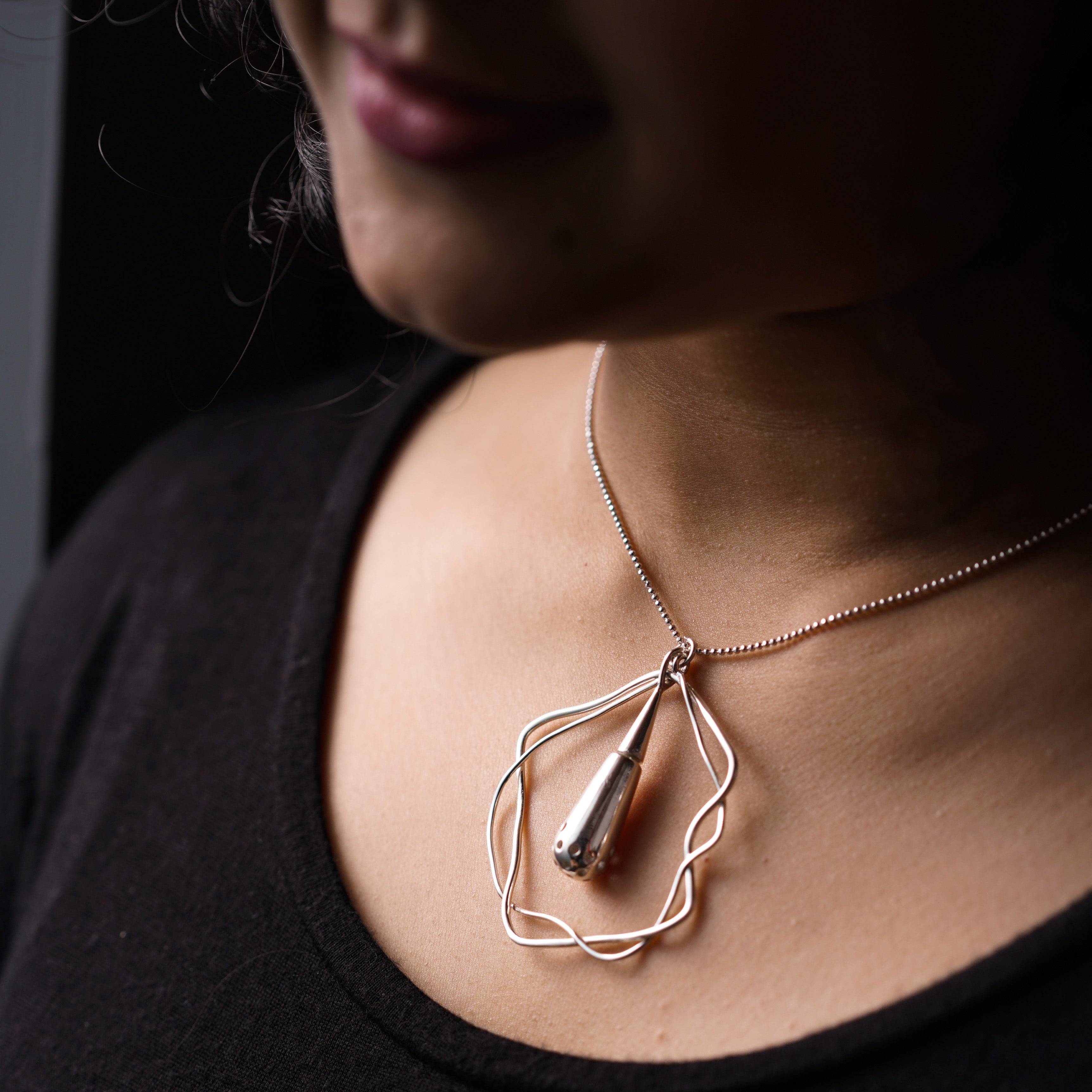 a woman wearing a necklace with a wire wrapped around it