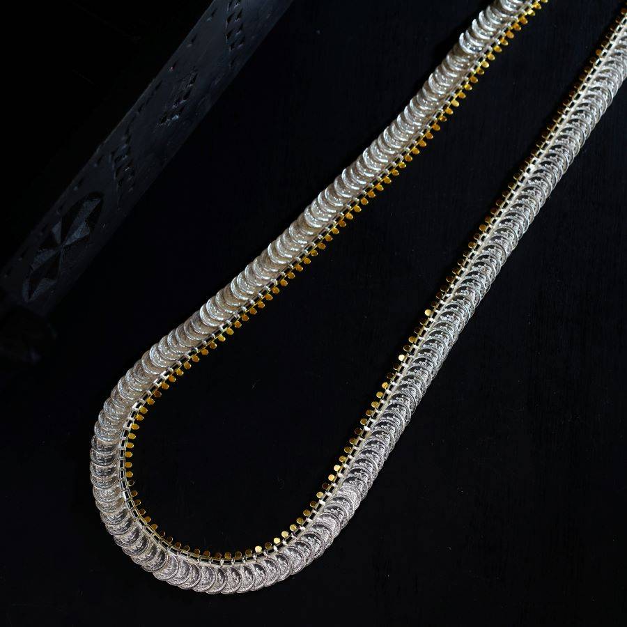 a silver chain with a gold clasp on a black background