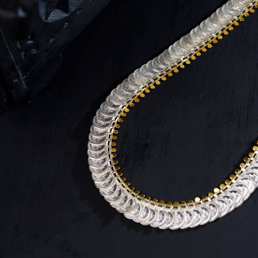 a gold and silver necklace on a black surface