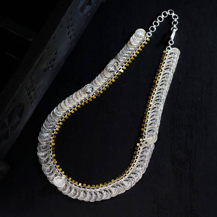 a silver and gold necklace on a black surface