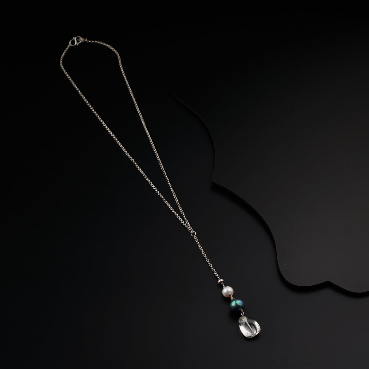 a silver necklace with a pearl and a chain