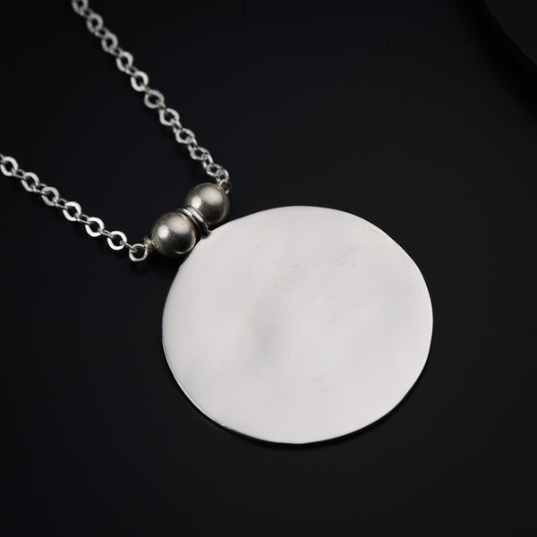 a white disc on a chain on a black surface