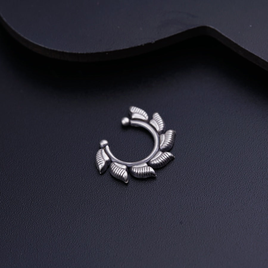 a silver ring with leaves on it sitting on a black surface