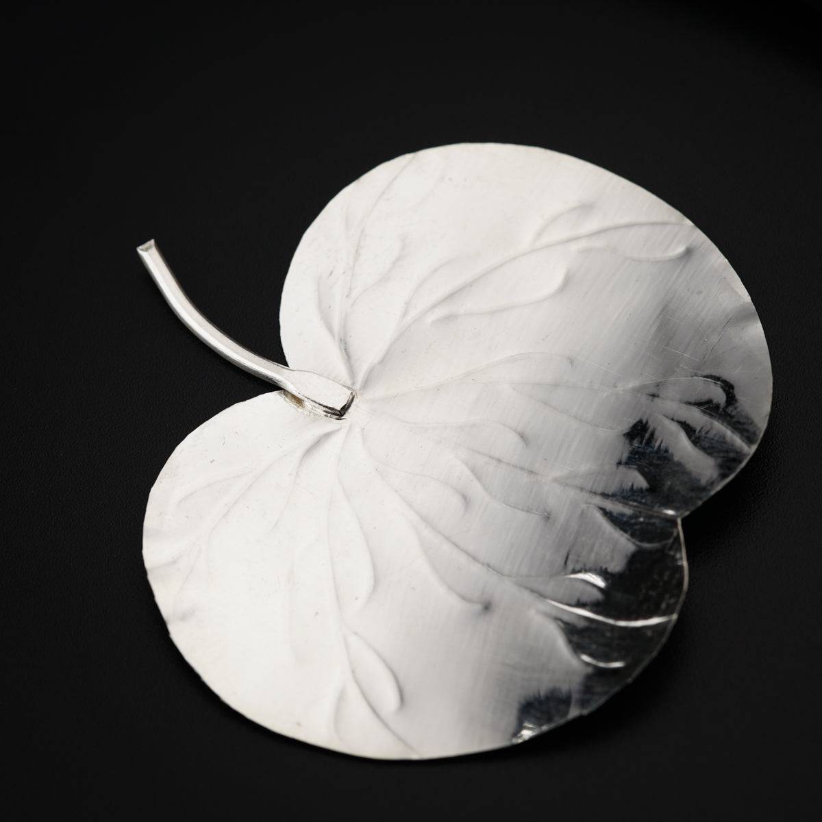 a silver plate with a leaf on it