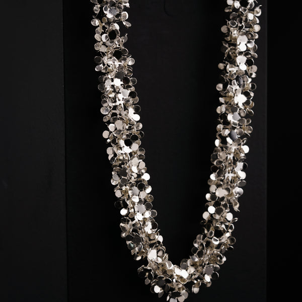 a long necklace with silver beads on a black background