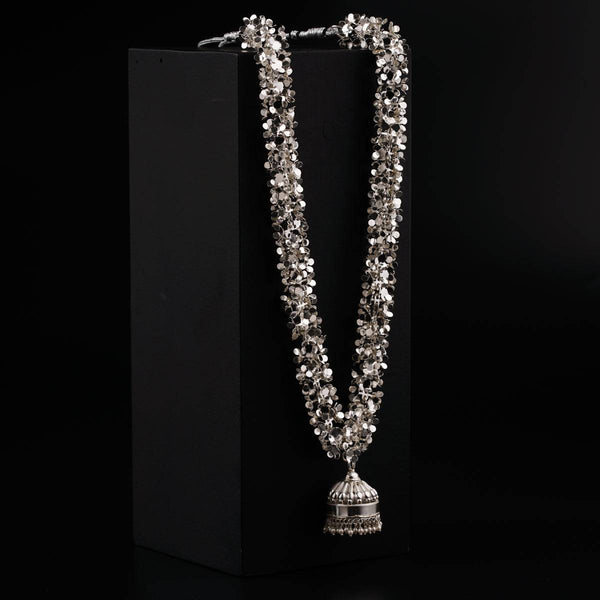 a silver necklace with a bell on a black background