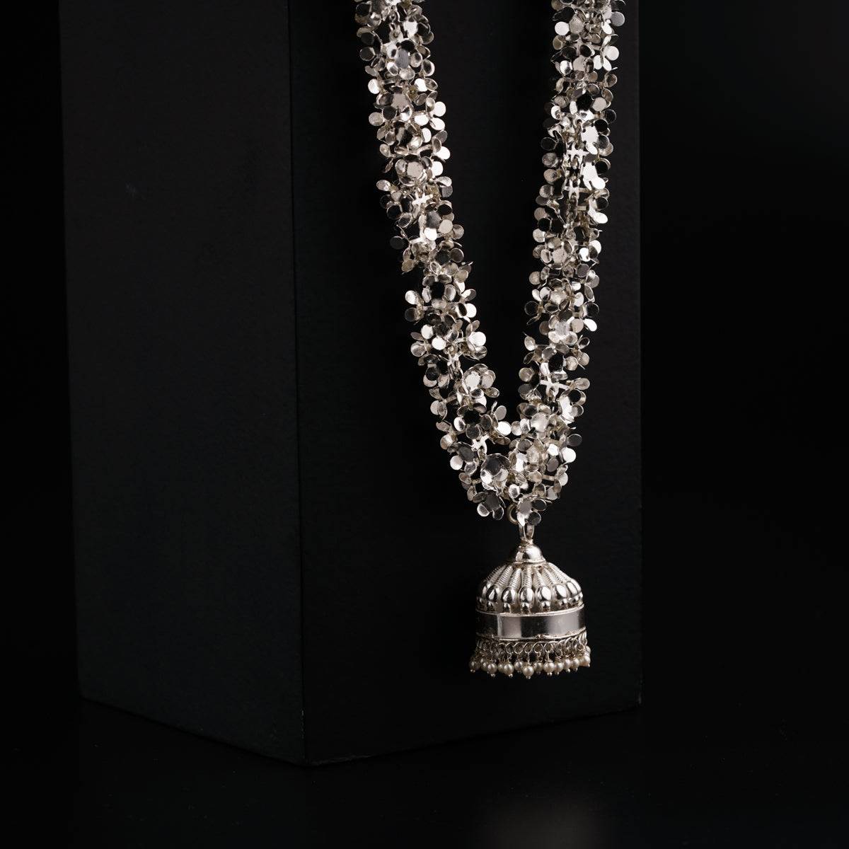 a necklace with a bell on a black background