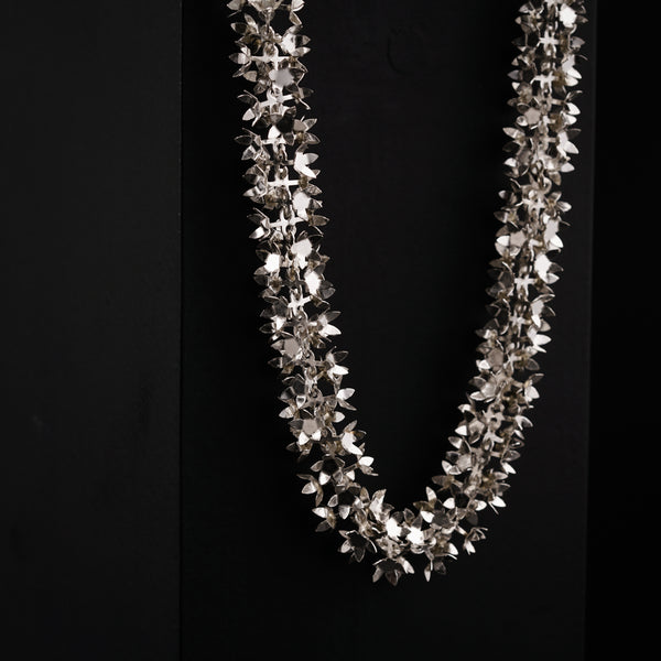 a necklace with silver flowers on a black background