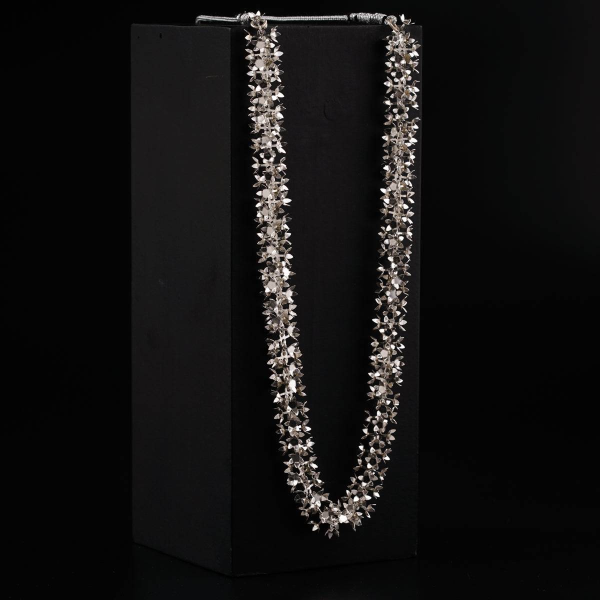 a long necklace is displayed in a black box