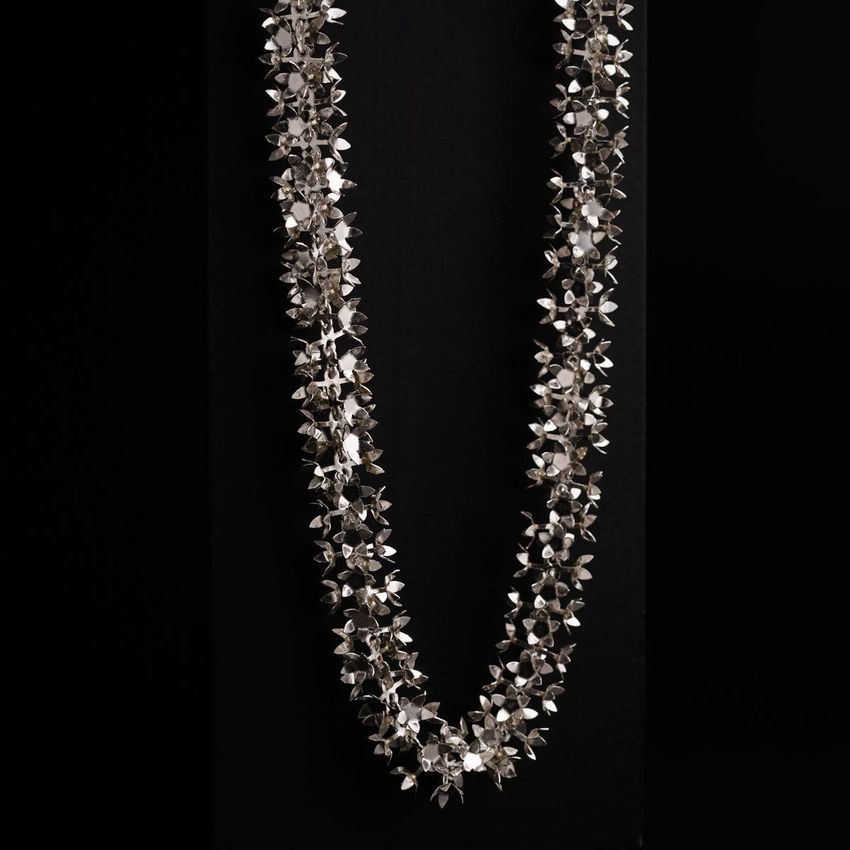 a long necklace with silver beads on a black background
