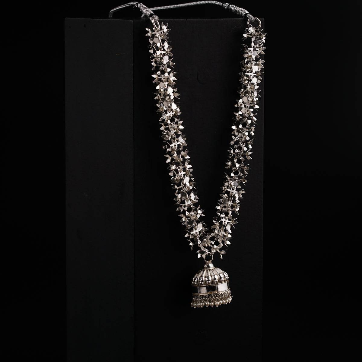 a silver necklace with a bell hanging from it