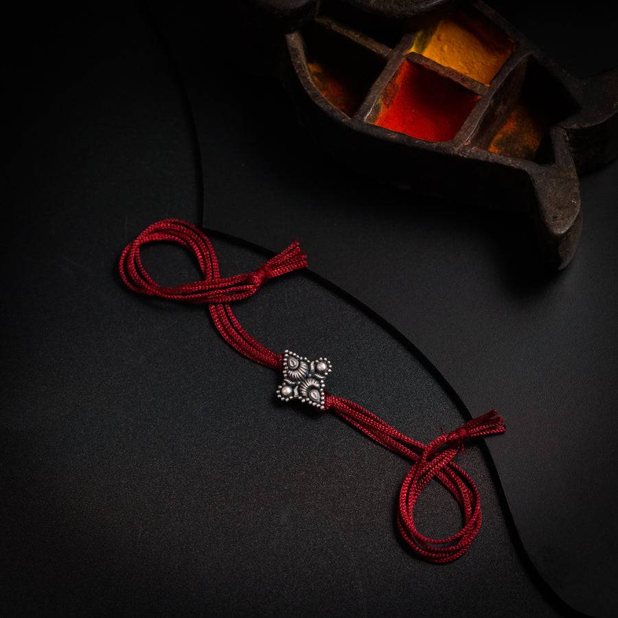 a red cord with two silver beads on it