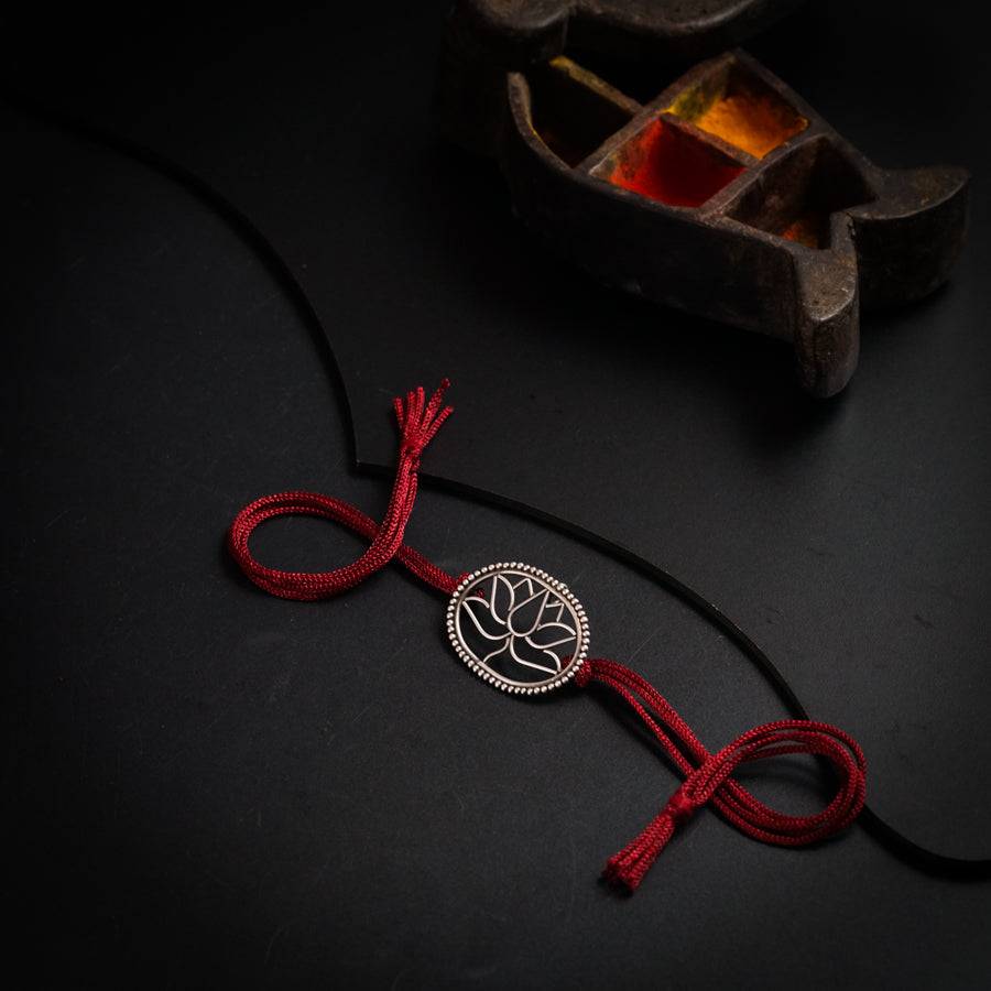 a red cord with a tree of life pendant on it
