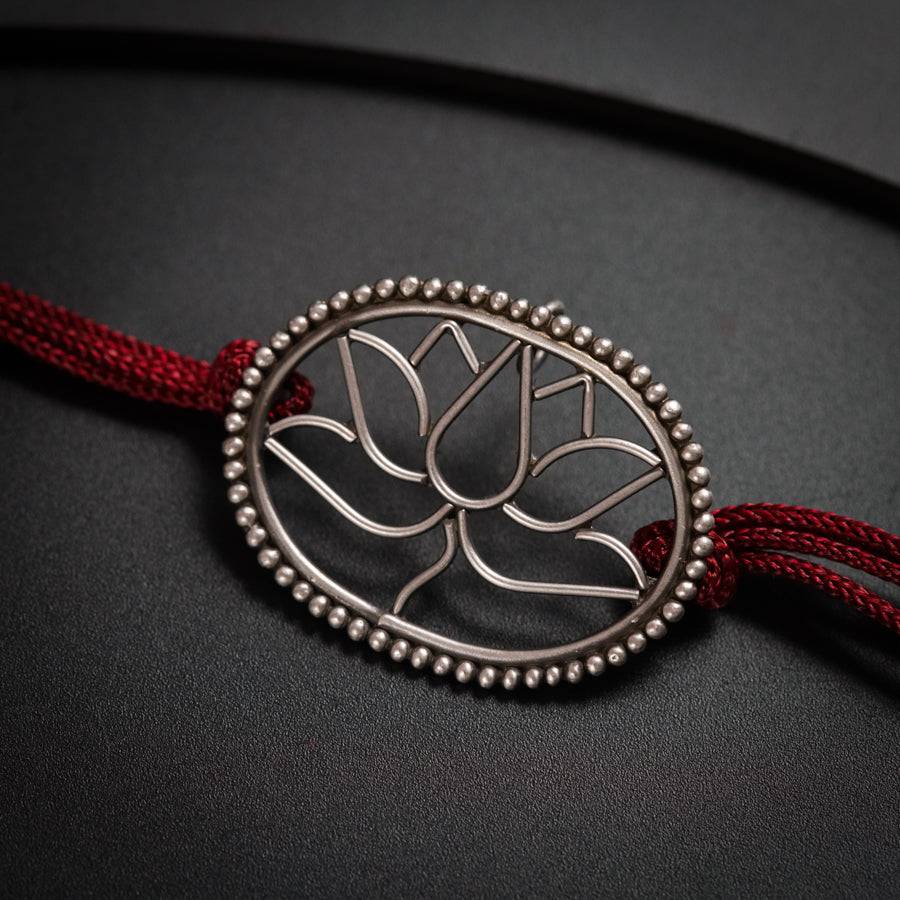 a red string bracelet with a tree of life pendant