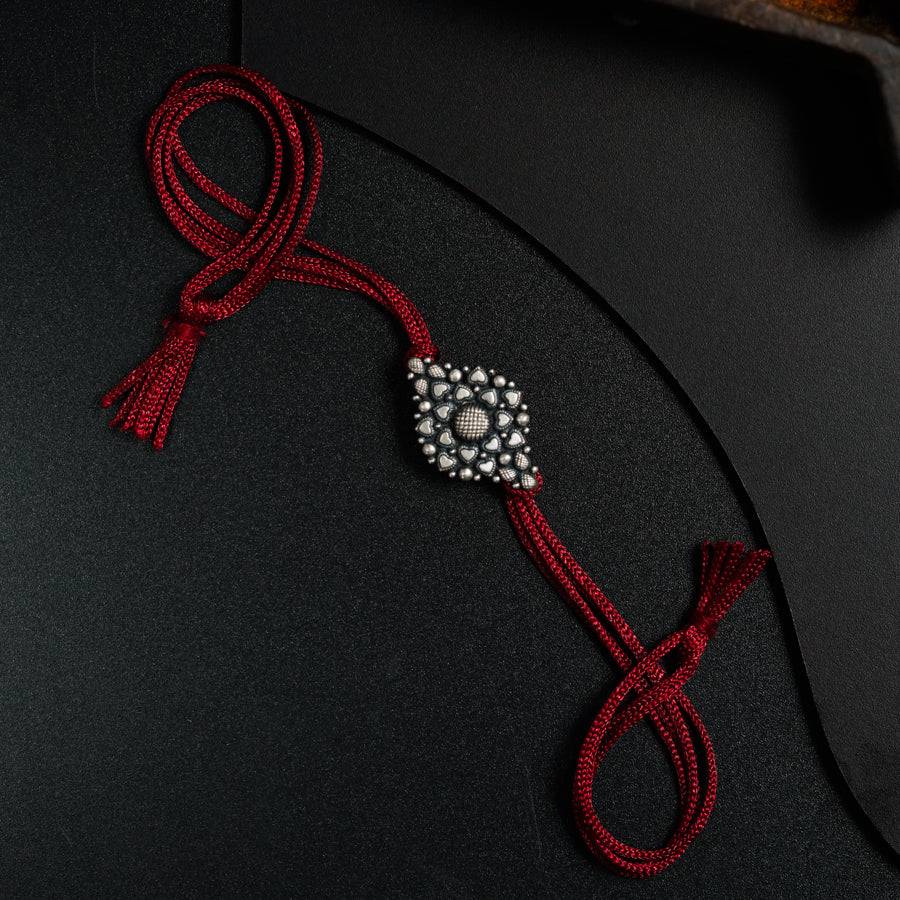 a red cord with a beaded brooch attached to it