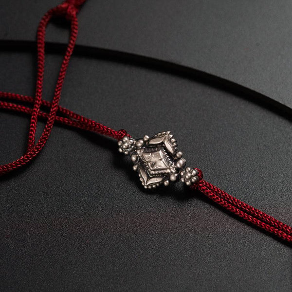 a close up of a red string with a silver bead