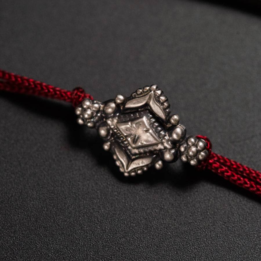 a close up of a red cord with a silver bead