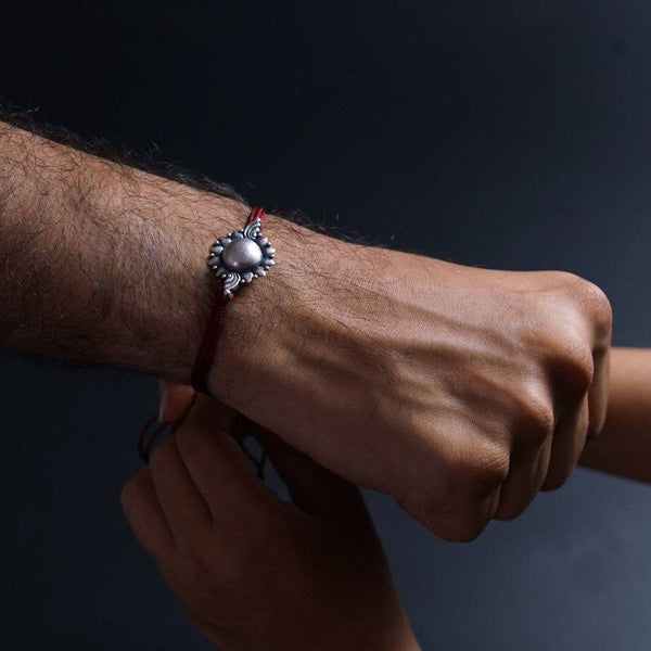 a man wearing a bracelet with a pearl on it
