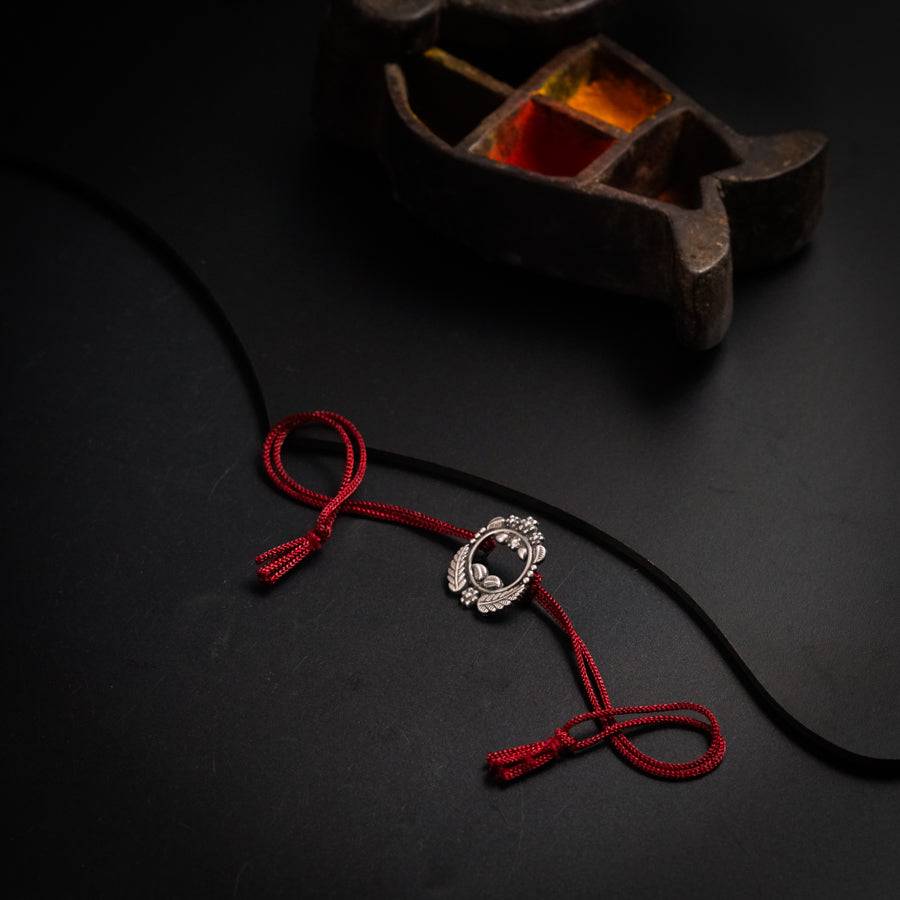 a red string with a silver clasp on a black surface