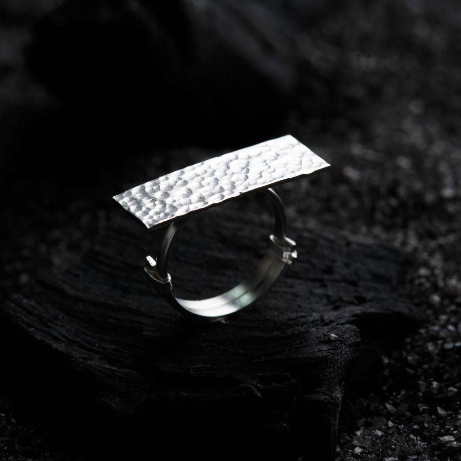 a silver ring sitting on top of a piece of wood
