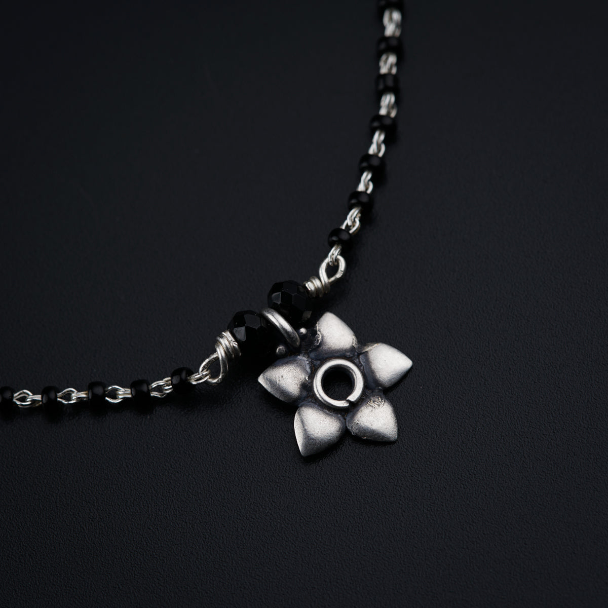 a black and silver necklace with a flower on it