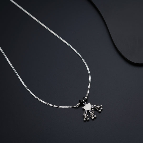 a black and white photo of a necklace on a black surface