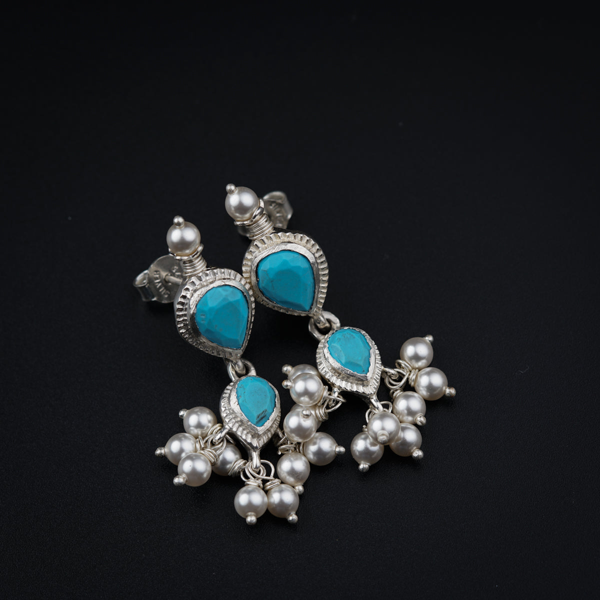 a pair of earrings with turquoise stones and pearls
