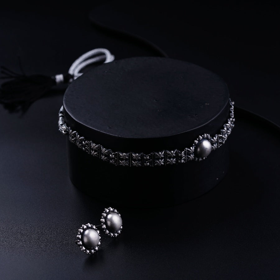 a black box with two pearls and a tassel