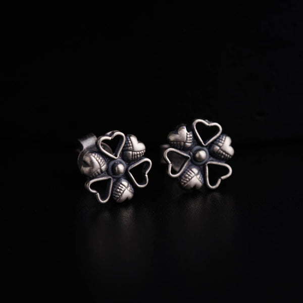 a pair of silver earrings on a black surface
